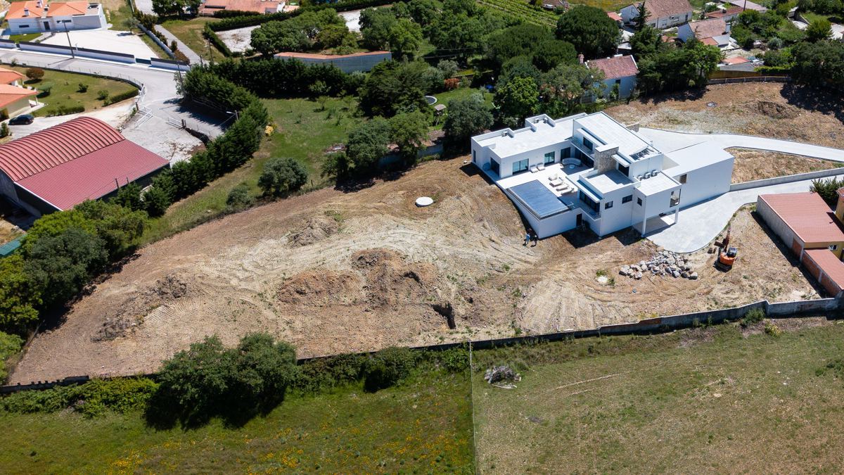 Moradia contemporânea vista de cima, com o terreno envolvente em obra