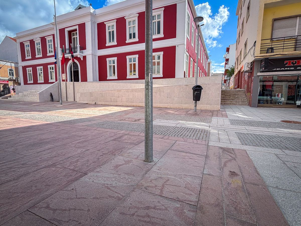 Largo requalificado em frente a um edifício histórico, com pavimento de pedra e grelhas de drenagem